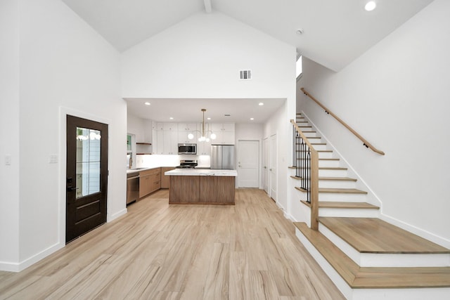 3907 Sumpter St, Houston, TX 77020 - kitchen featuring appliances with stainless steel finishes, high vaulted ceiling, a center island, light countertops, and light wood-style floors