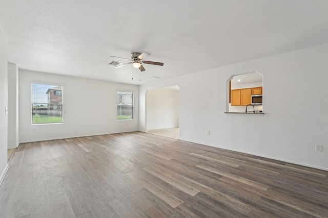 2607 Ensbrook Meadow Ln, Katy, TX 77449 - unfurnished room with healthy amount of natural light, a ceiling fan, wood finished floors, and arched walkways