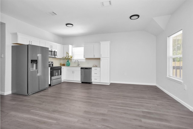 4412 Sayers St, Houston, TX 77026 - kitchen with appliances with stainless steel finishes, white cabinets, light countertops, wood finished floors, and lofted ceiling