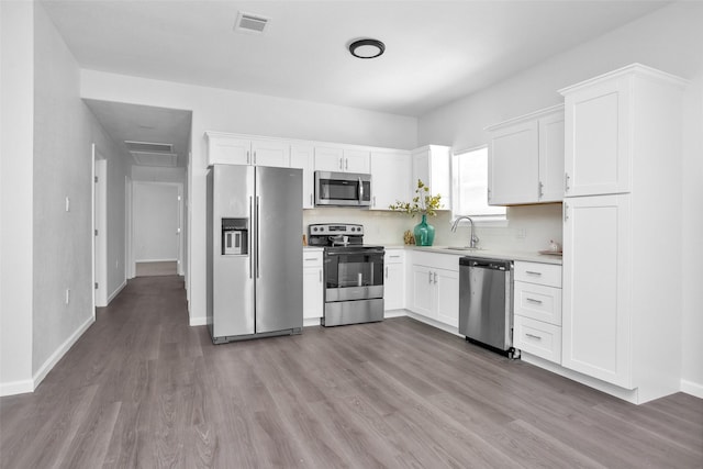 4412 Sayers St, Houston, TX 77026 - kitchen featuring stainless steel appliances, wood finished floors, light countertops, and white cabinetry