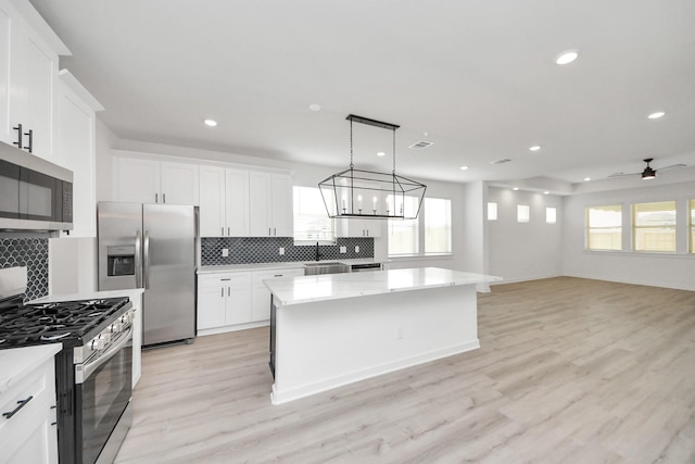 5318 Latigo Ct, Alvin, TX 77511 - kitchen with stainless steel appliances, a kitchen island, backsplash, white cabinets, and recessed lighting