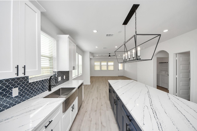 5318 Latigo Ct, Alvin, TX 77511 - kitchen with white cabinetry, washer and clothes dryer, backsplash, stainless steel dishwasher, and light wood finished floors