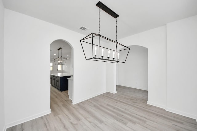 5318 Latigo Ct, Alvin, TX 77511 - unfurnished dining area with a chandelier, arched walkways, and light wood-style floors