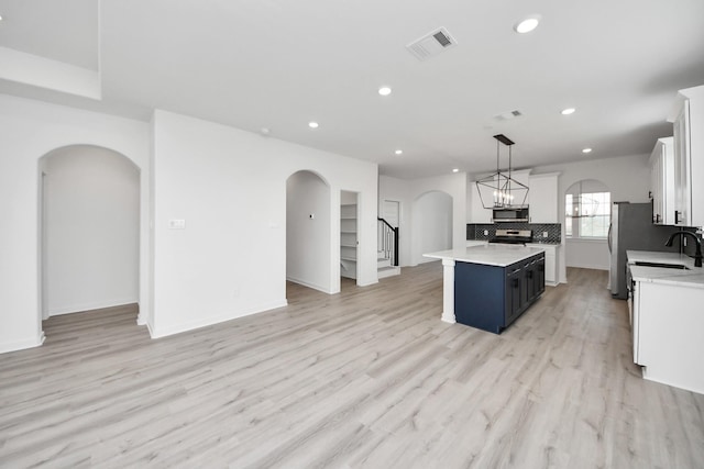 5318 Latigo Ct, Alvin, TX 77511 - kitchen featuring arched walkways, stainless steel appliances, a center island, light countertops, and recessed lighting