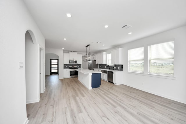 5318 Latigo Ct, Alvin, TX 77511 - kitchen with appliances with stainless steel finishes, a kitchen island, white cabinets, light countertops, and backsplash