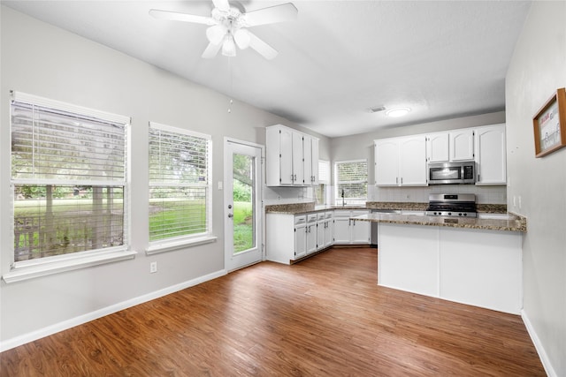 3327 Shady Glen Ln, Missouri City, TX 77459 - kitchen with appliances with stainless steel finishes, white cabinets, dark wood-style flooring, a peninsula, and a ceiling fan