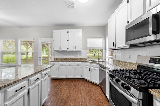 3327 Shady Glen Ln, Missouri City, TX 77459 - kitchen featuring appliances with stainless steel finishes, dark wood-style flooring, white cabinetry, and decorative backsplash