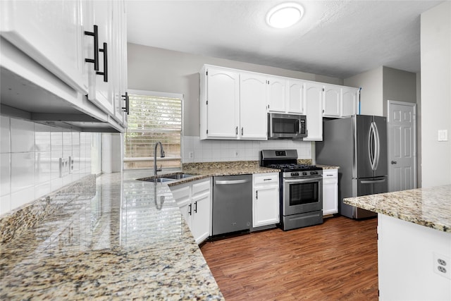 3327 Shady Glen Ln, Missouri City, TX 77459 - kitchen with appliances with stainless steel finishes, white cabinetry, dark wood-style flooring, and light stone countertops