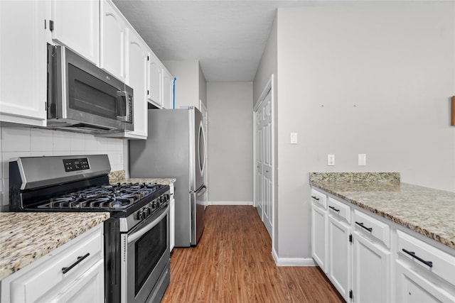 3327 Shady Glen Ln, Missouri City, TX 77459 - kitchen with stainless steel appliances, backsplash, white cabinetry, wood finished floors, and light stone counters