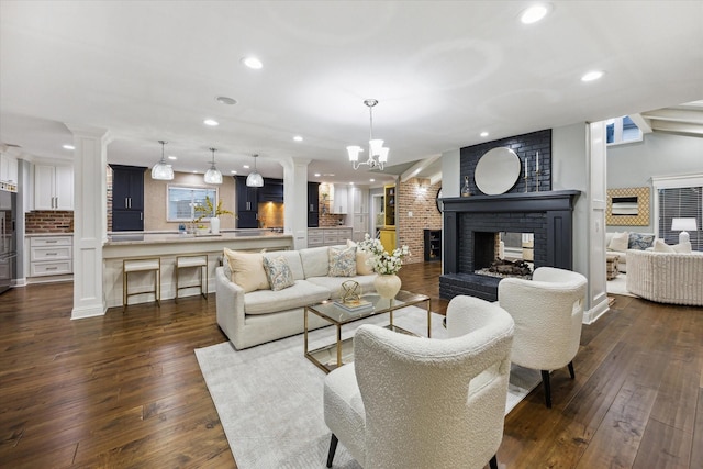 206 Lakemere St, Houston, TX 77079 - living area featuring ornate columns, a brick fireplace, recessed lighting, dark wood-style flooring, and a chandelier