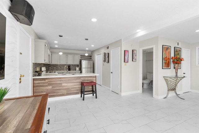 13530 Sharpbill Dr, Houston, TX 77083 - kitchen featuring freestanding refrigerator, light countertops, light marble finish floors, a peninsula, and recessed lighting