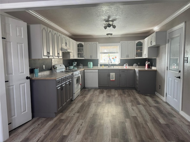308 S 11th St, La Porte, TX 77571 - kitchen with white appliances, gray cabinets, under cabinet range hood, dark wood finished floors, and glass insert cabinets