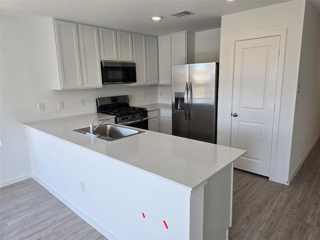 314 Nicholas Rd, Wharton, TX 77488 - kitchen featuring stainless steel appliances, wood finished floors, light countertops, a peninsula, and recessed lighting