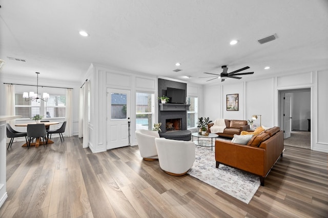 16235 Salmon Ln, Spring, TX 77379 - living room with a decorative wall, a fireplace, wood finished floors, recessed lighting, and a chandelier