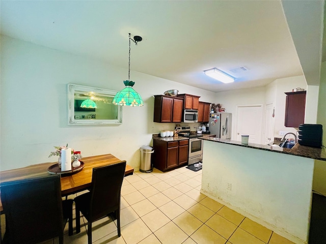9458 Grand Spark Dr, Rosharon, TX 77583 - kitchen featuring appliances with stainless steel finishes, a peninsula, light tile patterned flooring, hanging light fixtures, and dark stone countertops