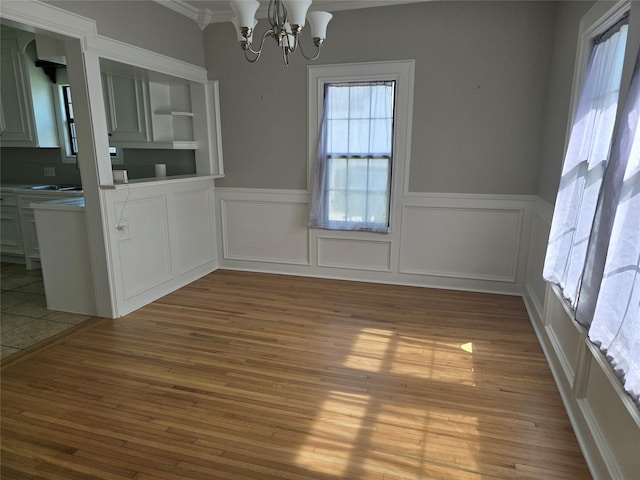 604 N Main St, Galena Park, TX 77547 - unfurnished dining area with crown molding, a chandelier, wood finished floors, a wainscoted wall, and a decorative wall
