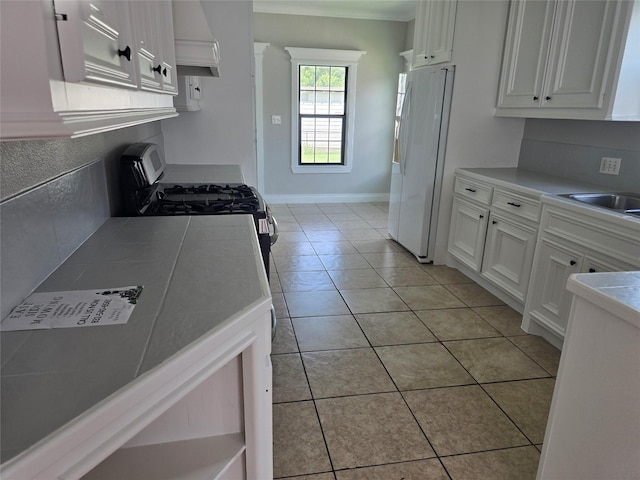 604 N Main St, Galena Park, TX 77547 - kitchen with freestanding refrigerator, stainless steel gas range, white cabinetry, custom exhaust hood, and light countertops