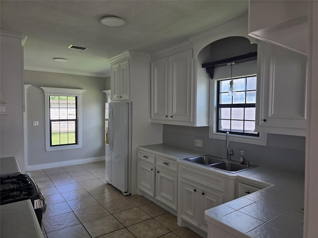604 N Main St, Galena Park, TX 77547 - kitchen featuring freestanding refrigerator, tile counters, gas range, white cabinetry, and crown molding