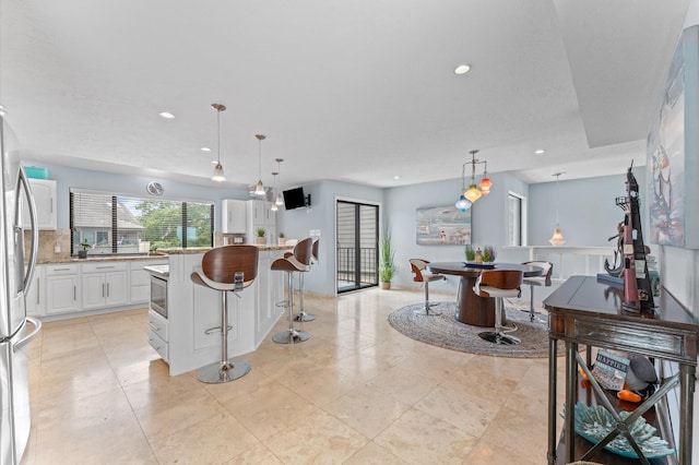2816 Lighthouse Dr, Houston, TX 77058 - kitchen featuring stainless steel refrigerator with ice dispenser, light stone countertops, white cabinets, a breakfast bar area, and recessed lighting