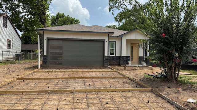 2418 Centennial St, Liberty, TX 77575 - view of front facade featuring board and batten siding, stone siding, a garage, a shingled roof, and driveway