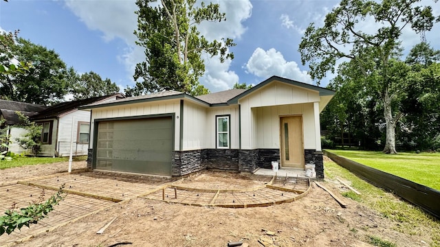2418 Centennial St, Liberty, TX 77575 - view of front of home with an attached garage, stone siding, driveway, board and batten siding, and a front lawn