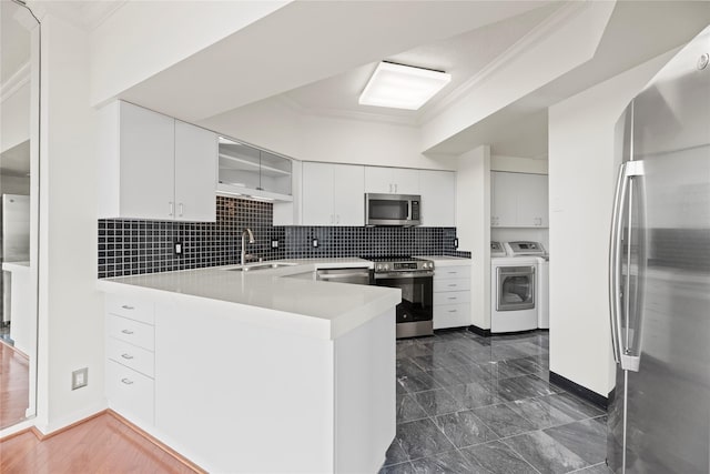 1111 Bering Dr Unit 1001, Houston, TX 77057 - kitchen featuring appliances with stainless steel finishes, washing machine and clothes dryer, a peninsula, crown molding, and backsplash