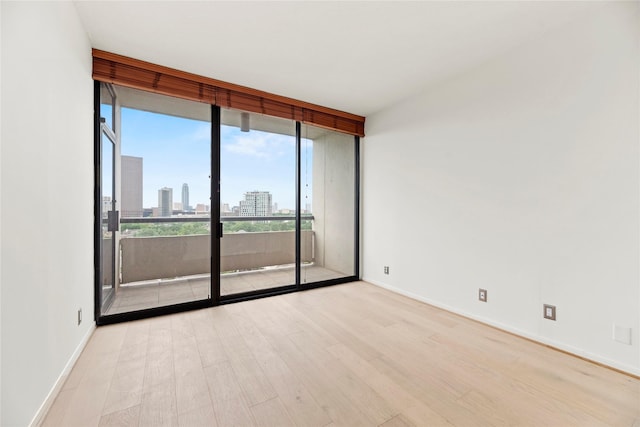 1111 Bering Dr Unit 1001, Houston, TX 77057 - unfurnished room featuring a wall of windows, light wood finished floors, and a view of skyline
