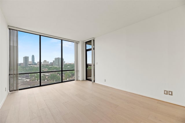 1111 Bering Dr Unit 1001, Houston, TX 77057 - spare room with a wall of windows, light wood-style flooring, and a skyline view