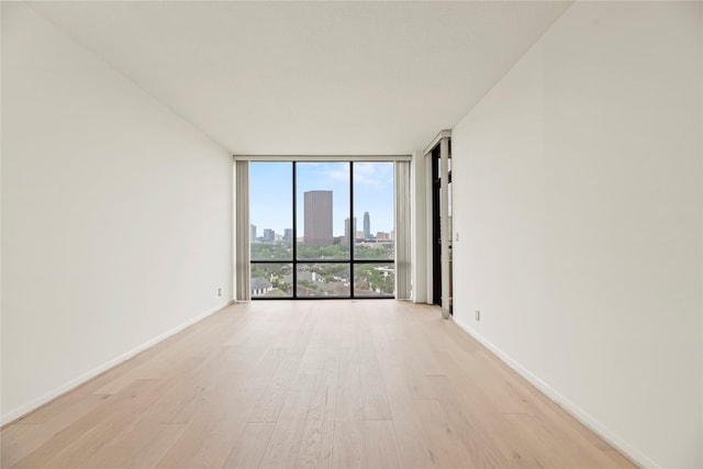 1111 Bering Dr Unit 1001, Houston, TX 77057 - unfurnished room featuring floor to ceiling windows, light wood finished floors, and a skyline view
