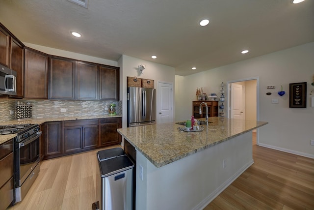 1009 Old Vine, Brenham, TX 77833 - kitchen featuring stainless steel appliances, light wood-type flooring, light stone countertops, backsplash, and dark brown cabinets