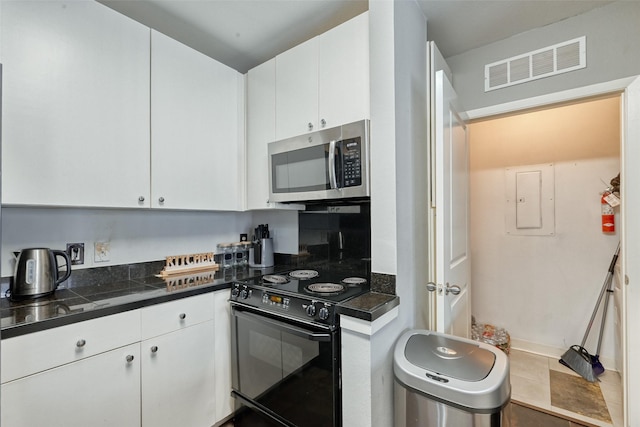 3505 Sage Rd Unit 1206, Houston, TX 77056 - kitchen featuring stainless steel microwave, electric range, electric panel, white cabinets, and tile counters