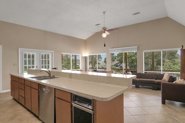 63 Harbour Row Dr, Coldspring, TX 77331 - kitchen featuring open floor plan, high vaulted ceiling, light tile patterned flooring, stainless steel dishwasher, and a kitchen island with sink