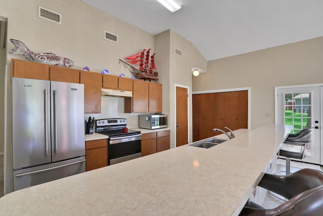 63 Harbour Row Dr, Coldspring, TX 77331 - kitchen featuring stainless steel appliances, under cabinet range hood, brown cabinetry, light countertops, and a kitchen bar