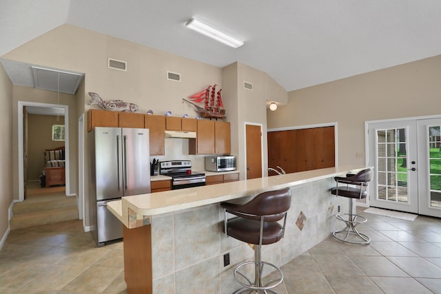 63 Harbour Row Dr, Coldspring, TX 77331 - kitchen with appliances with stainless steel finishes, under cabinet range hood, light countertops, high vaulted ceiling, and light tile patterned flooring