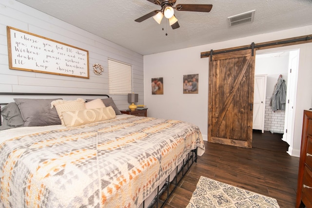 3405 Randall St, Pearland, TX 77581 - bedroom with a barn door, dark wood-type flooring, wooden walls, a textured ceiling, and a ceiling fan