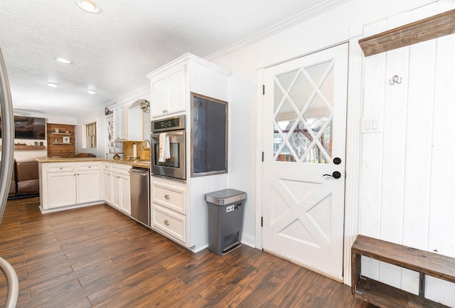 3405 Randall St, Pearland, TX 77581 - kitchen featuring stainless steel appliances, a peninsula, crown molding, white cabinets, and dark wood finished floors
