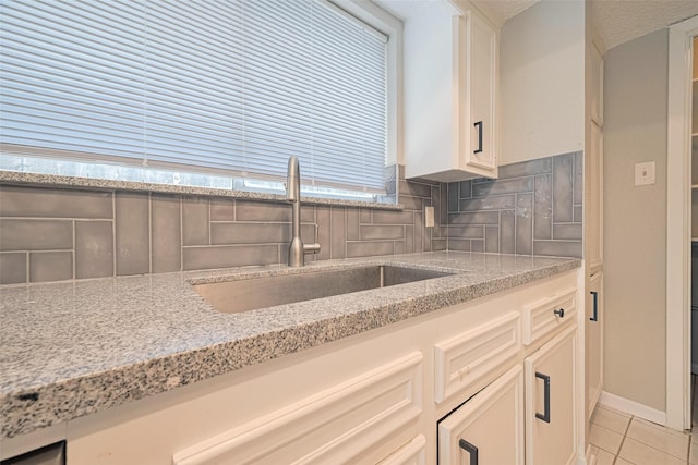 6822 Stonewater, Houston, TX 77084 - kitchen featuring light stone countertops, decorative backsplash, light tile patterned floors, and white cabinets