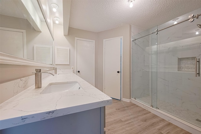 6822 Stonewater, Houston, TX 77084 - full bathroom featuring double vanity, a textured ceiling, a marble finish shower, and wood finished floors