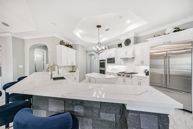 9503 Martha Springs Dr, Houston, TX 77070 - kitchen with built in appliances, arched walkways, a raised ceiling, recessed lighting, and a peninsula