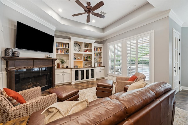 59 N Berryline Cir, Spring, TX 77381 - living room featuring dark wood-style flooring, a ceiling fan, a raised ceiling, a tiled fireplace, and ornamental molding