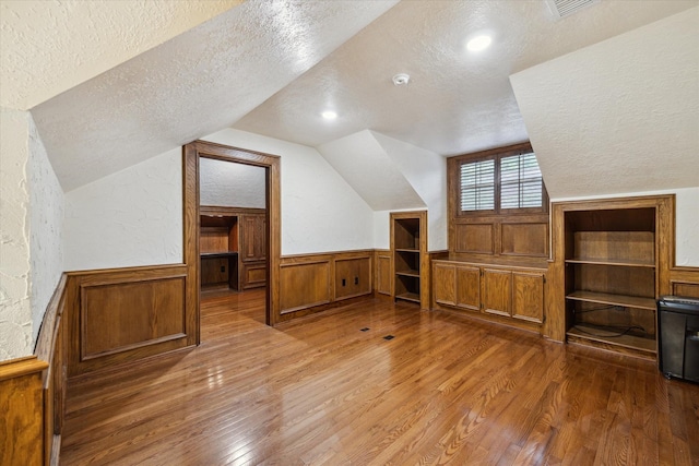 59 N Berryline Cir, Spring, TX 77381 - additional living space with a textured ceiling, wood finished floors, vaulted ceiling, wainscoting, and a textured wall
