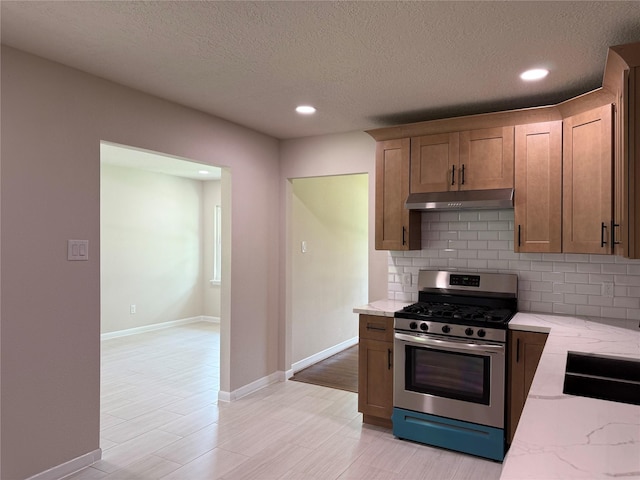 6202 Simsdale St, Houston, TX 77087 - kitchen featuring gas range, under cabinet range hood, light stone counters, tasteful backsplash, and recessed lighting