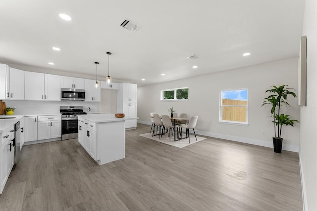 200 Burnett Dr, Baytown, TX 77520 - kitchen with stainless steel appliances, recessed lighting, a kitchen island, light wood finished floors, and light countertops