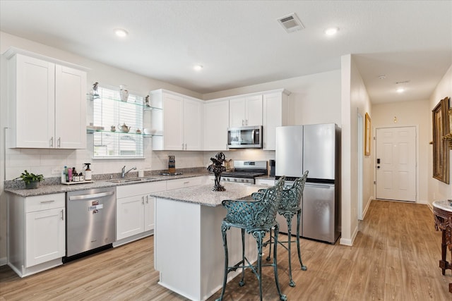 23502 Glenbuck St, Spring, TX 77373 - kitchen with appliances with stainless steel finishes, white cabinetry, backsplash, light wood finished floors, and recessed lighting