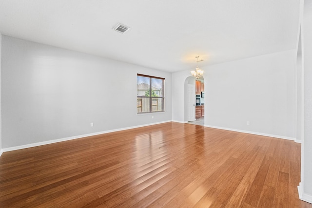 18203 Park Sage Ct, Cypress, TX 77433 - empty room with arched walkways, light wood-style floors, and a chandelier