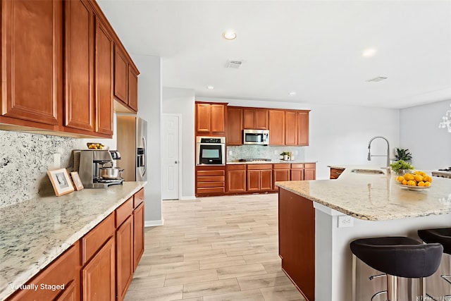 18203 Park Sage Ct, Cypress, TX 77433 - kitchen featuring appliances with stainless steel finishes, a kitchen bar, backsplash, brown cabinetry, and recessed lighting