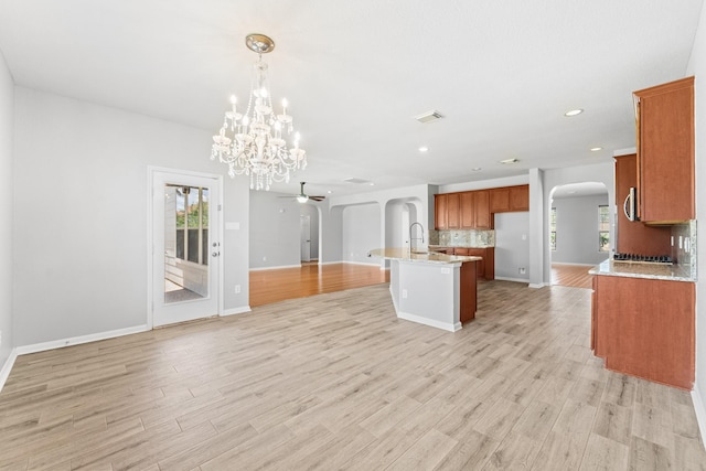 18203 Park Sage Ct, Cypress, TX 77433 - kitchen with arched walkways, open floor plan, brown cabinets, ceiling fan, and decorative backsplash