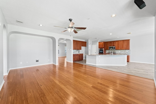 18203 Park Sage Ct, Cypress, TX 77433 - unfurnished living room featuring arched walkways, a ceiling fan, light wood-style flooring, and recessed lighting