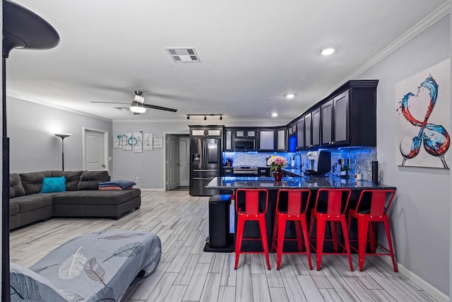902 51st St, Galveston, TX 77551 - kitchen with stainless steel appliances, dark countertops, light wood-style floors, a peninsula, and crown molding