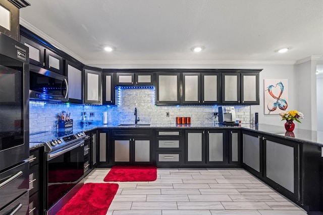 902 51st St, Galveston, TX 77551 - kitchen with stainless steel appliances, ornamental molding, dark cabinetry, decorative backsplash, and dark stone counters